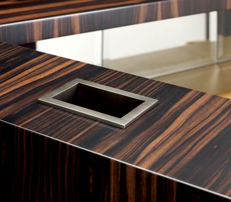 Detail of Bacco, a wooden cabinet-bar with several accessories inside and bronze base, profiles and handles, from Promemoria's catalogue | Promemoria